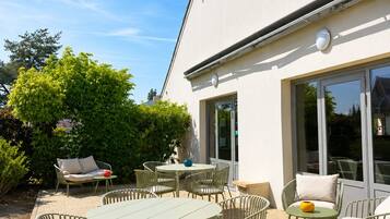Un espace extérieur aménagé en terrasse, avec une table et des chaises, un canapé et une plante en pot.