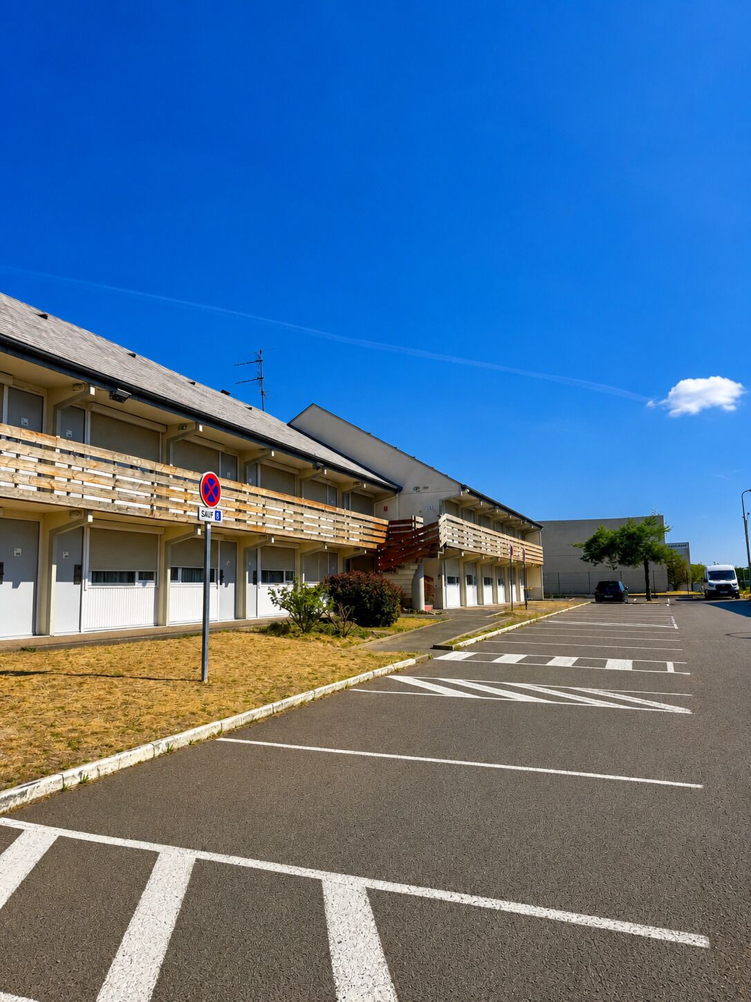 A motel with a parking lot, a stop sign, and a clear blue sky.