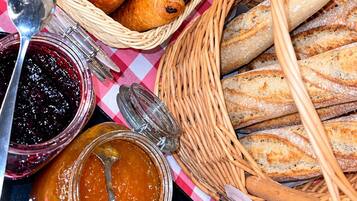 Een tafel met manden vol gebak en brood, en potten vol jam.