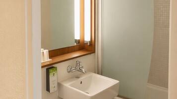 Een badkamer met een wit wastafel, toilet en douche met een matglazen deur.