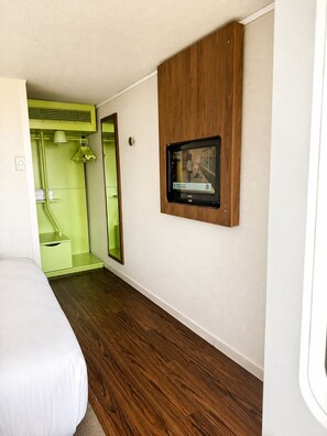 A room with a bed, a television mounted on the wall, and a mirror. - Campanile Orleans Saran (Saran)