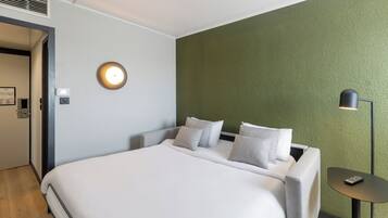 Een hotelkamer met een bed, een nachtkastje, een lamp en een wandlamp.