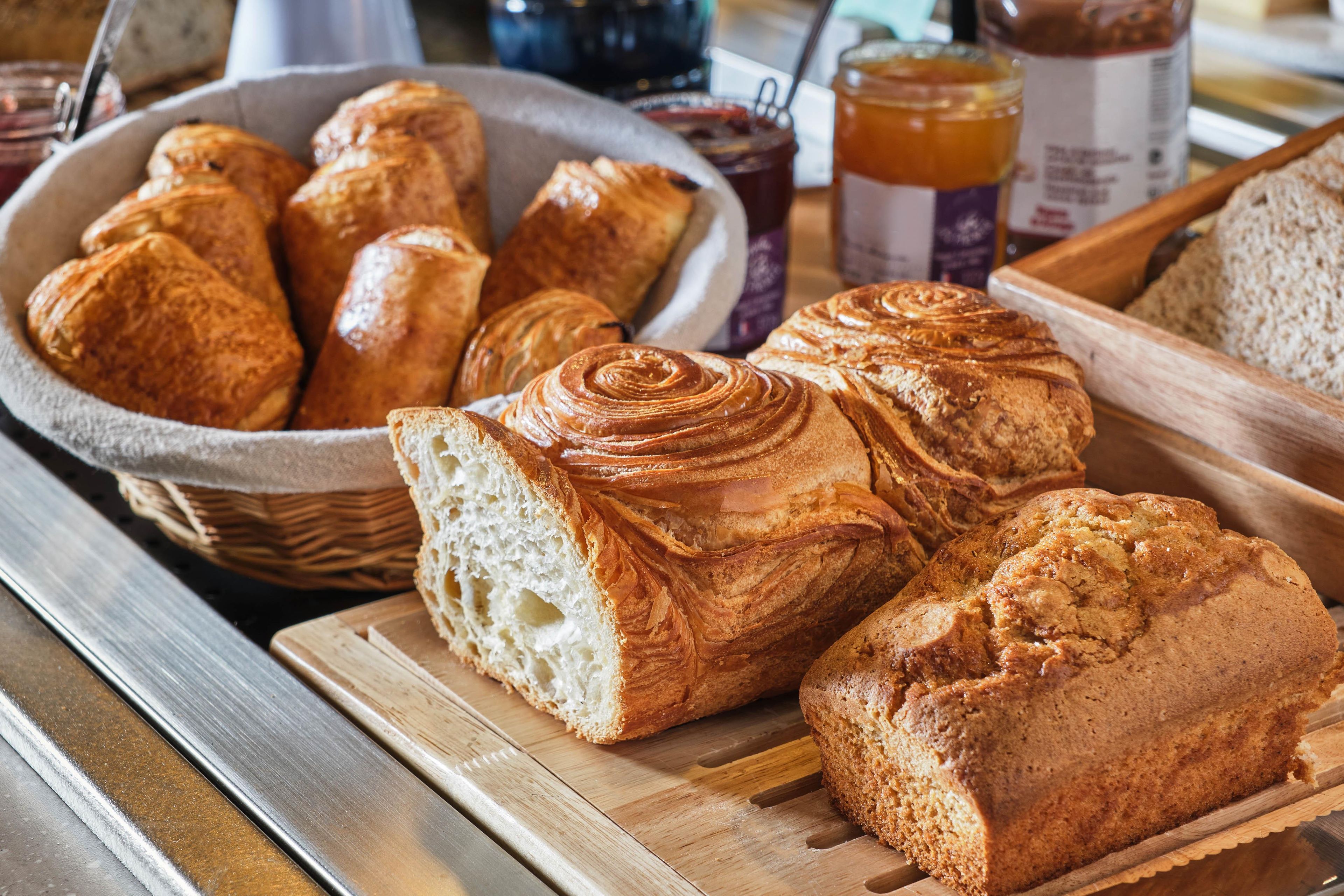 A variety of breads and pastries on a wooden table.