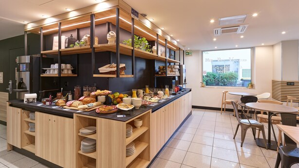 Una barra de desayuno con diversos alimentos y utensilios, estantes de madera y una ventana con vistas.