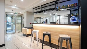 Zona de bar con taburetes, mostrador y estantería con botellas.