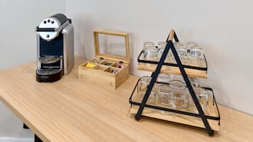 A coffee machine, a wooden box with compartments, and a glass display stand with multiple glasses.