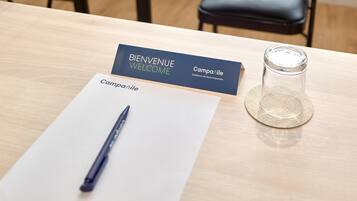A business card, a pen, and a glass of water on a table.
