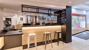 Eine Bar mit Stehtischen, einer Theke und einer Kreidetafel mit Speisekarte.