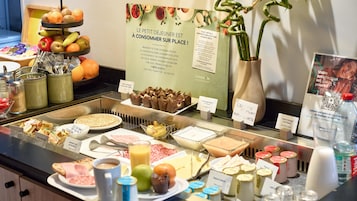 Un buffet proposant une variété de plats, notamment des fruits, des pâtisseries et des condiments.