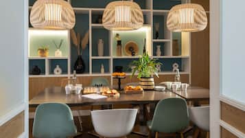 Un comedor con una mesa de madera, cuatro sillas y tres lámparas colgantes de ratán.