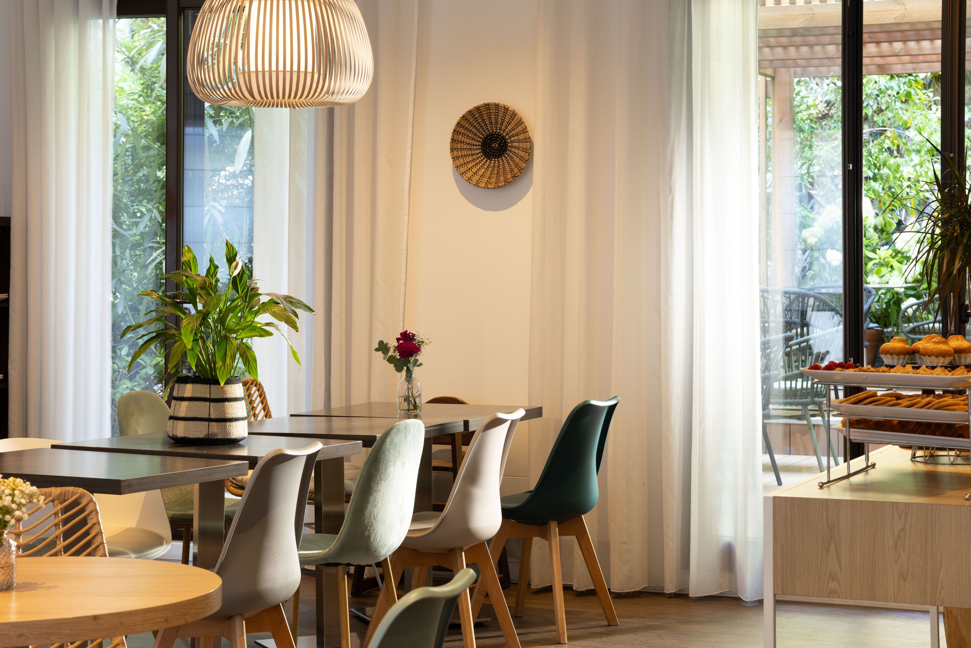 A dining area with a round table, chairs, a potted plant, and a hanging light fixture.
