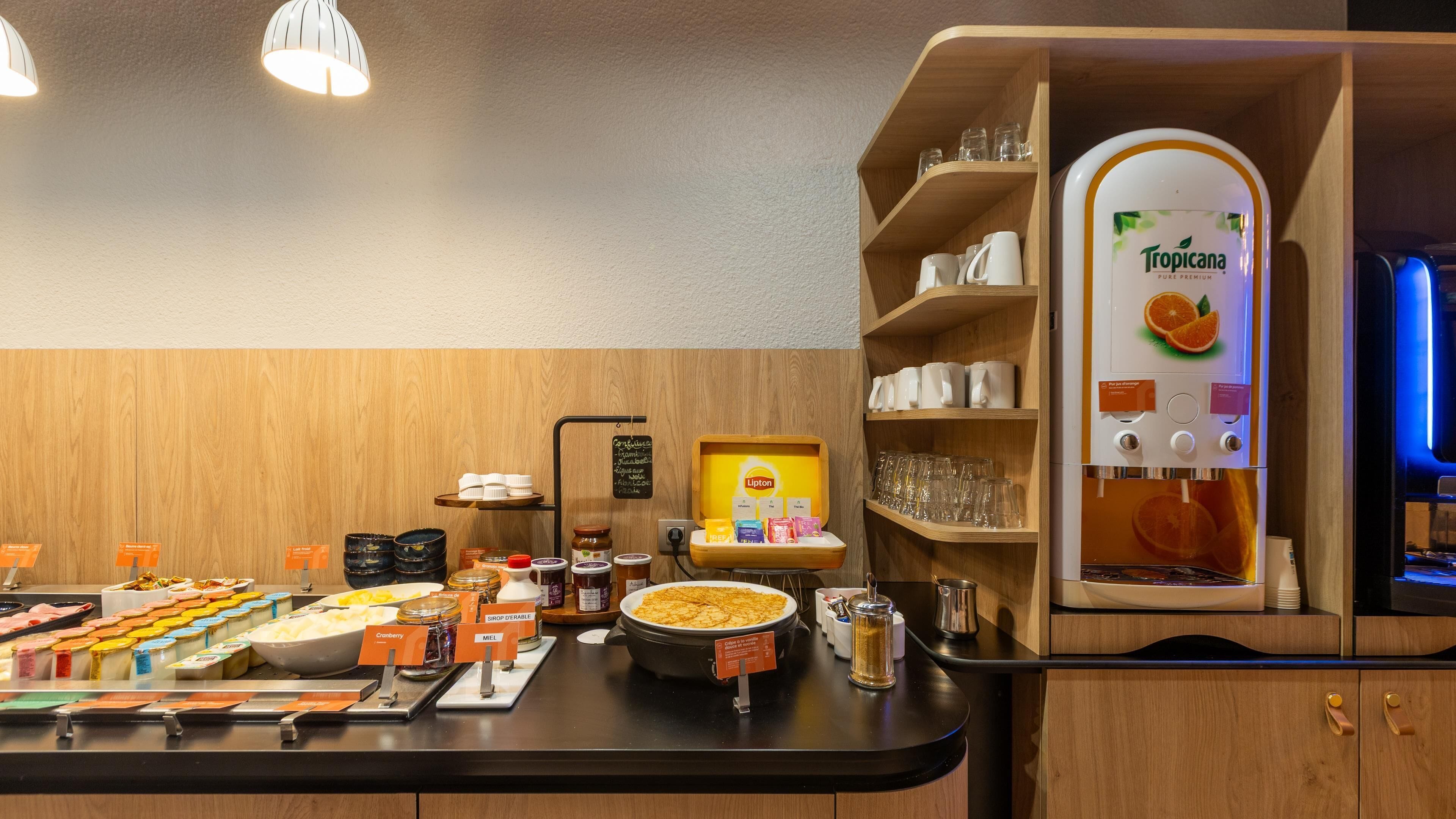 A breakfast bar with various food items, a coffee machine, and a juice dispenser.