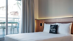 A hotel room with a large bed, a window with curtains, and a view of the outside balcony. - Moxy Paris Bastille France (Paris)