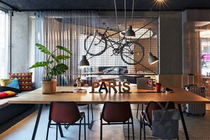 A modern workspace with a large table, chairs, a bicycle, and a "PARIS" sign.