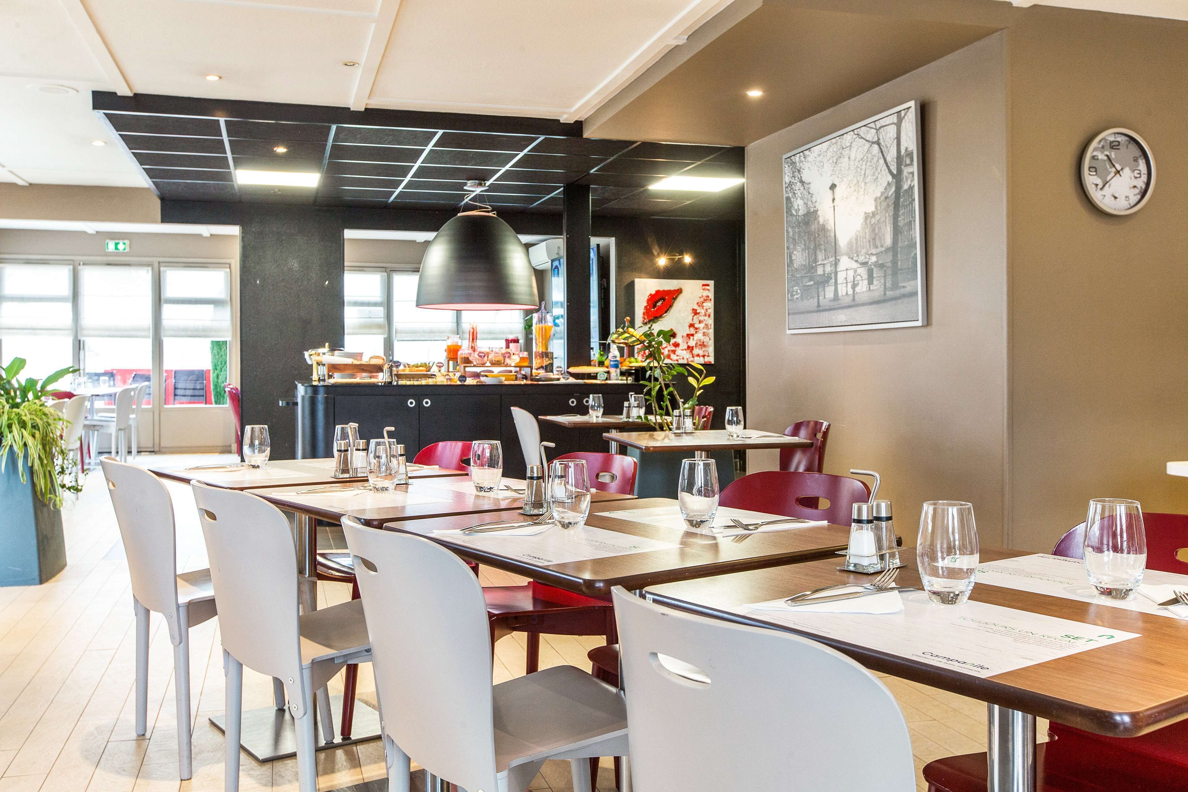 A modern dining area with tables set for two, equipped with water glasses and cutlery.