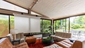 Ein modernes Wohnzimmer mit Ledersofas, einem Couchtisch und einem großen Fenster mit Blick auf einen Garten.