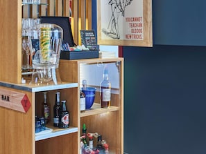 A bar area with a menu board, bottles, glasses, and a sign with a dog illustration.