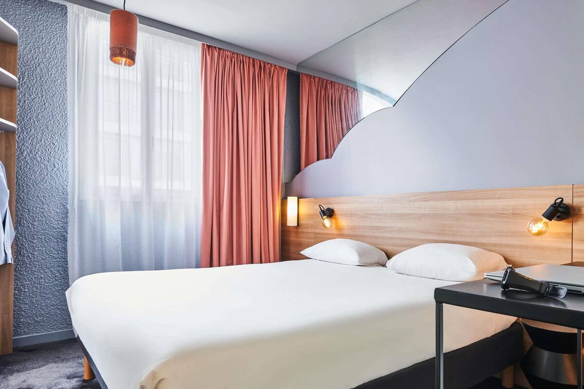 Une chambre d’hôtel moderne avec un grand lit, un bureau et une armoire.