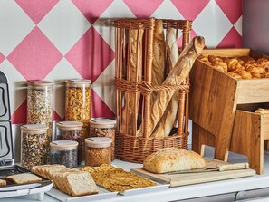 Un bufé de desayuno con panes, bollería y frascos de conservas.