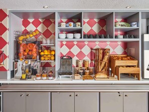 Une cuisine avec un mur de crédence orné d’un motif losangique rouge et blanc, divers aliments et différents appareils de cuisine.
