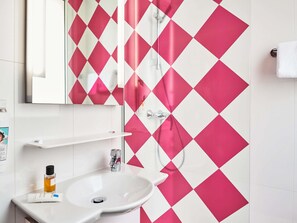 A bathroom with a white sink, a mirror, and a shower curtain with a diamond pattern. - ibis Styles Paris Alésia Montparnasse (Paris)
