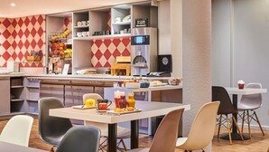 Un área de desayuno moderna con una barra, asientos y una cafetera.