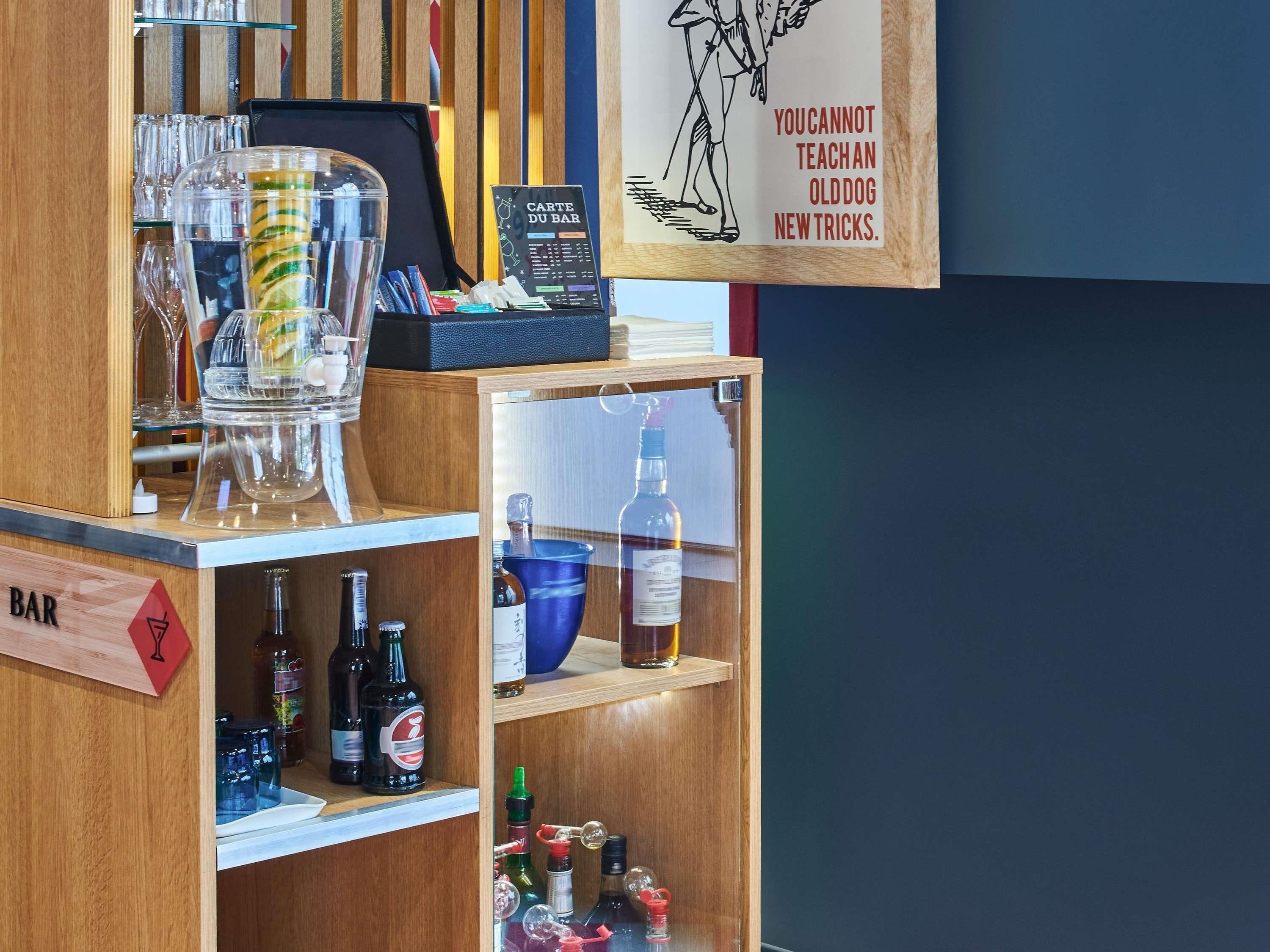 A bar area with a menu board, bottles, glasses, and a sign with a dog illustration.