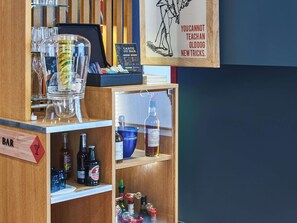 Un espace bar avec un tableau affichant le menu, des bouteilles, des verres et un panneau illustré avec un chien.