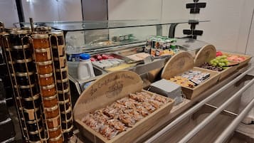 A buffet with various food items, including jars of preserves, packaged snacks, and fresh fruits.