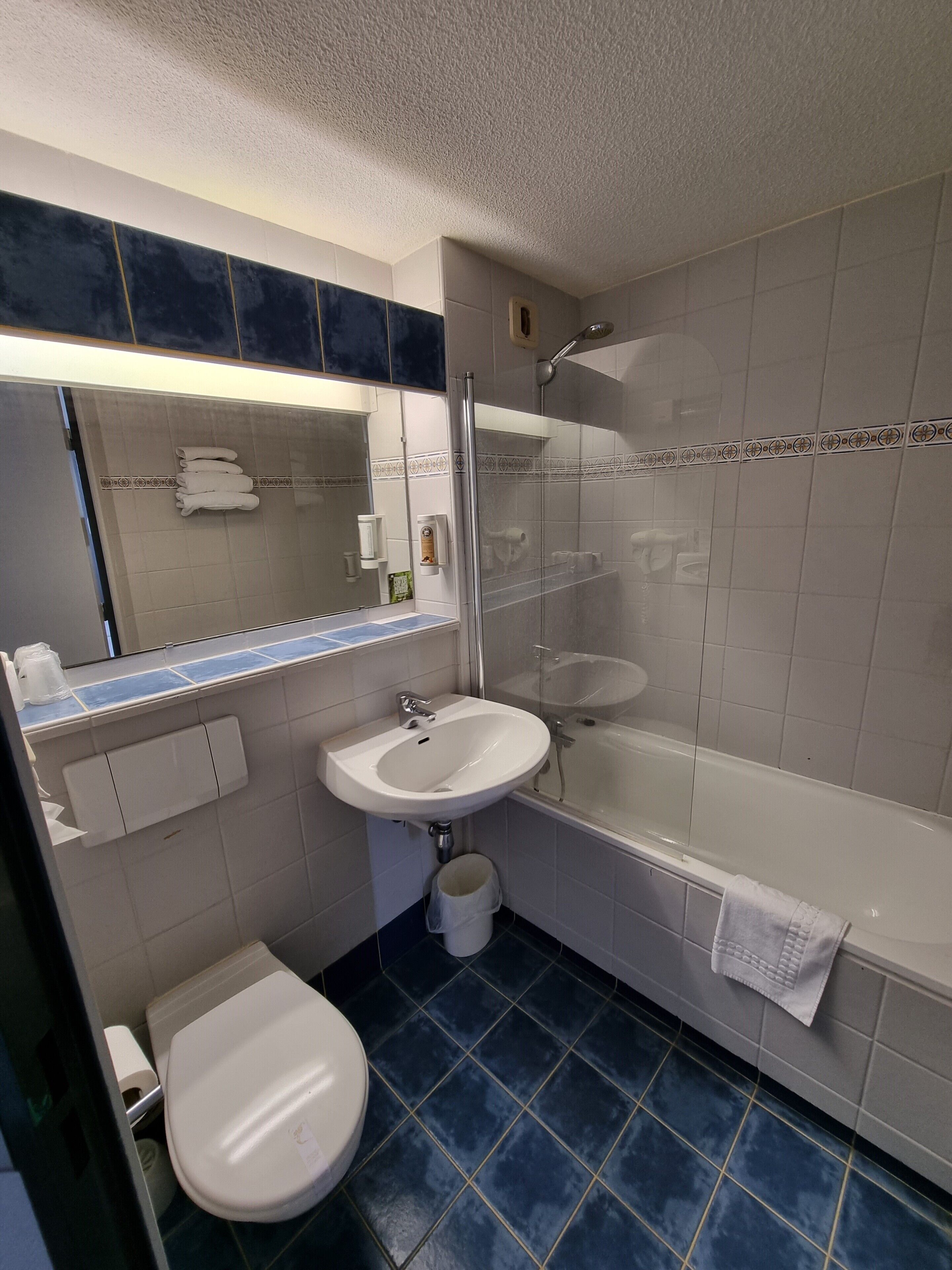 A bathroom with a sink, mirror, toilet, and shower.