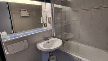 A bathroom with a sink, mirror, toilet, and shower.