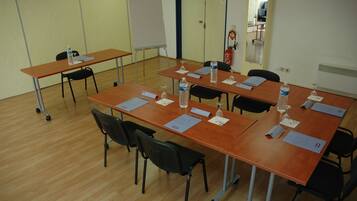 Un salón de conferencias con cuatro mesas, cada una con sillas, botellas de agua y tarjetas de identificación.
