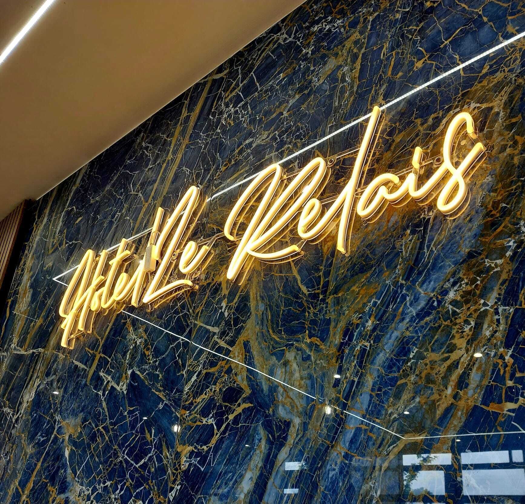 En neonskilte med teksten 'Mille Le Relais' på en marmorvæg.