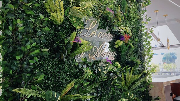 Una pared cubierta de diversas plantas y un letrero que dice "Le coin de l'ami".