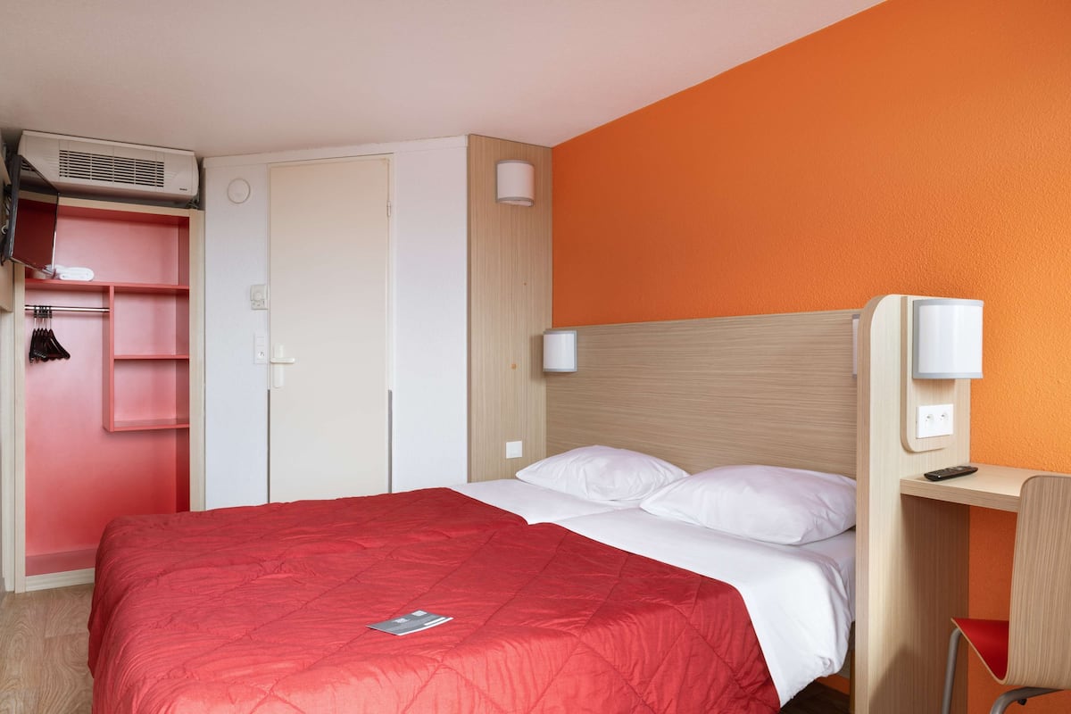 A hotel room with a bed, a wardrobe, a desk, and a chair.