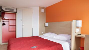 A hotel room with a bed, a wardrobe, a desk, and a chair.