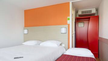 Una habitación de hotel con una cama, un armario rojo y un aire acondicionado de pared.