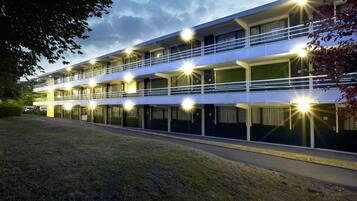 Un hotel de varios pisos con un diseño moderno, con balcones y un estacionamiento.