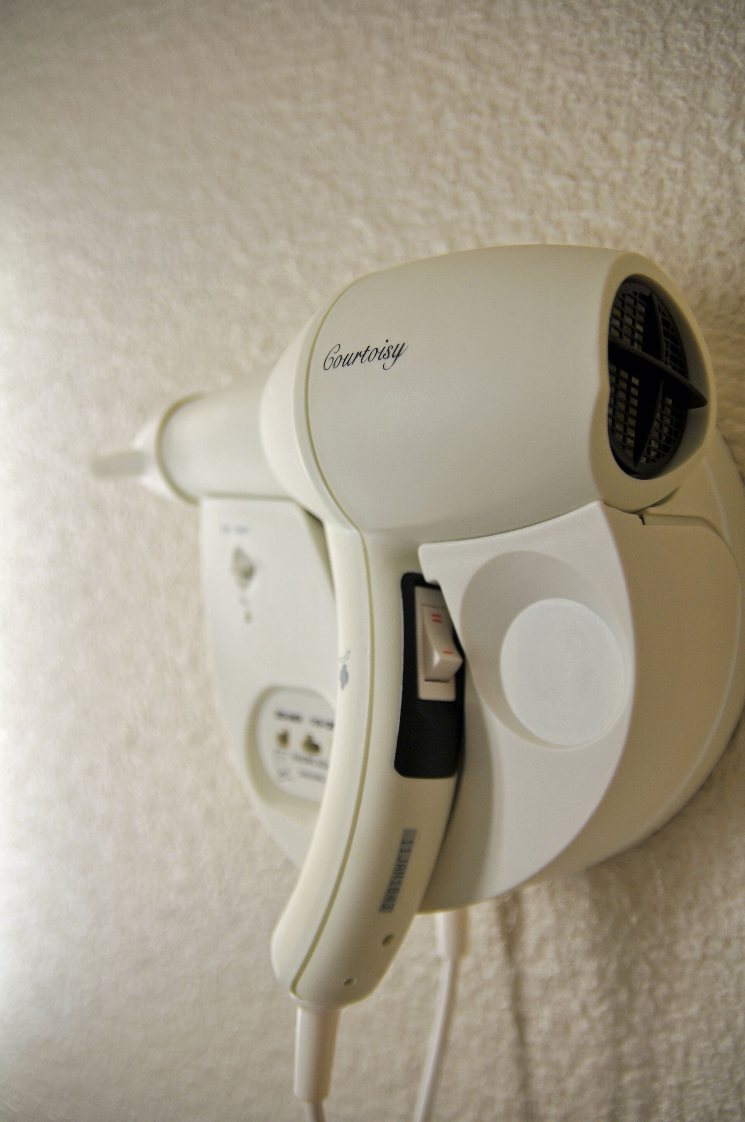 A white hair dryer with a control panel and a power cord.