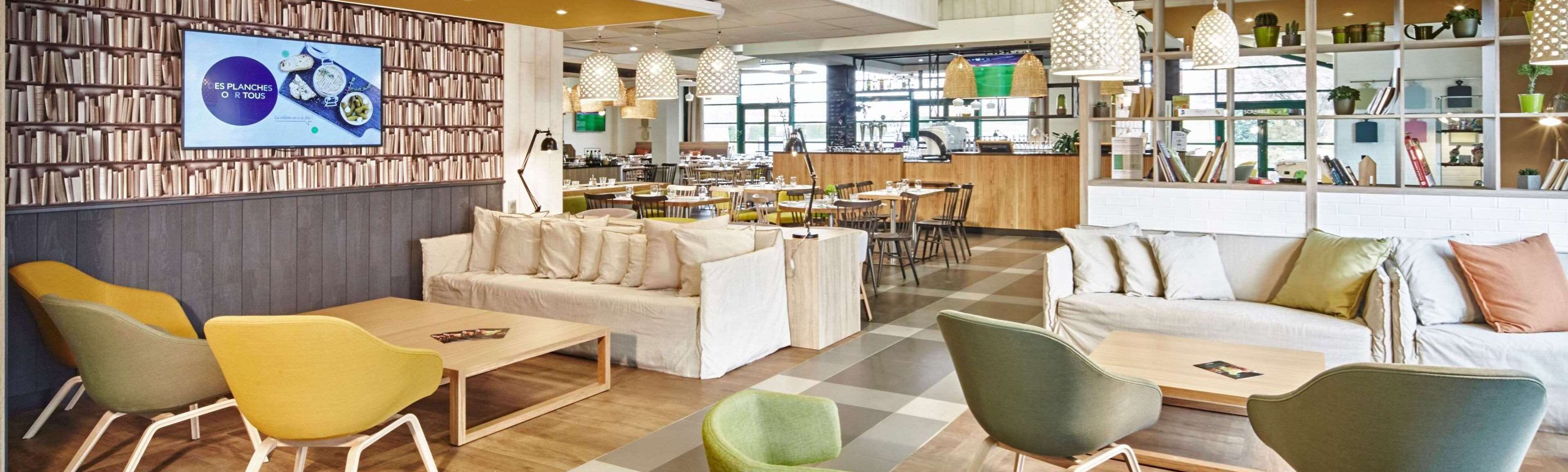 Ein modernes Café mit Schachbrettboden, Holztischen und einer Bücherwand voller Bücher.