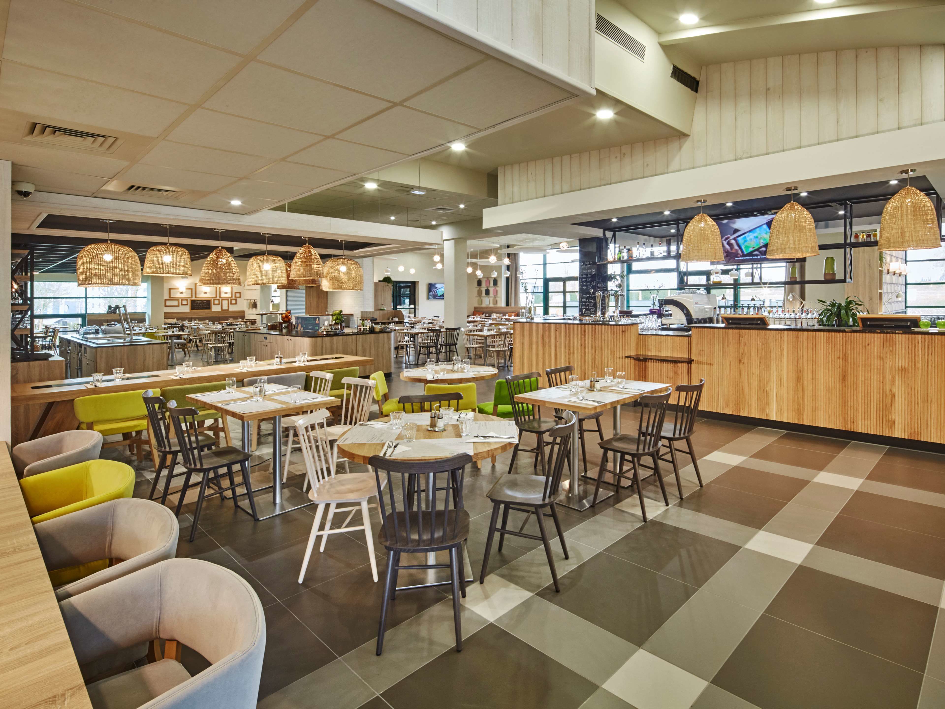 A spacious restaurant with multiple dining areas, a central bar, and a kitchen visible in the background.