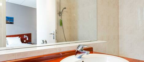 Un baño de hotel con un espejo grande, un lavabo y una ducha.