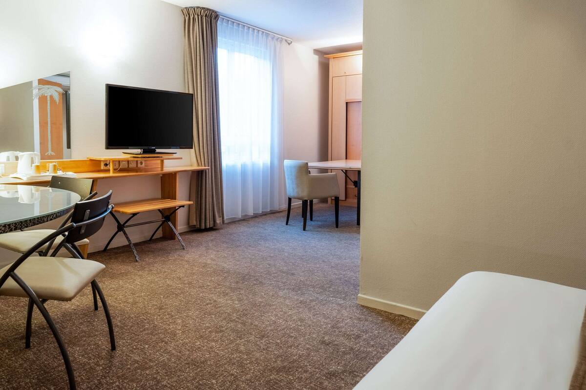 Une chambre d’hôtel équipée d’un bureau, d’une chaise, d’une télévision et d’un lit.