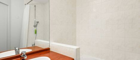 A bathroom with a wooden vanity, two sinks, a mirror, a shower, and a bathtub.