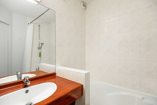 A bathroom with a wooden vanity, two sinks, a mirror, a shower, and a bathtub.