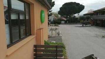A building with a green logo, a bench, and a parking lot.