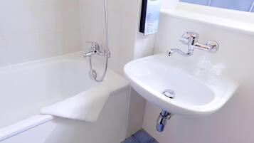 Un baño moderno con bañera, un lavamanos blanco y dispensador de jabón.