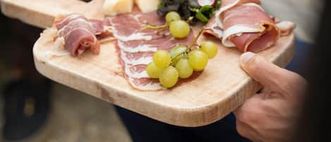 A wooden board with various cheeses, cured meats, and grapes.