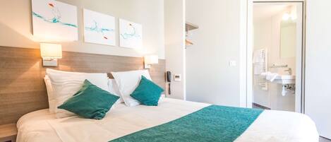 A hotel room with a bed, a nightstand, a telephone, and a wall-mounted light.