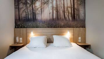 Un dormitorio con una cama grande, dos mesitas de noche, un teléfono en la pared y un cuadro de un bosque.